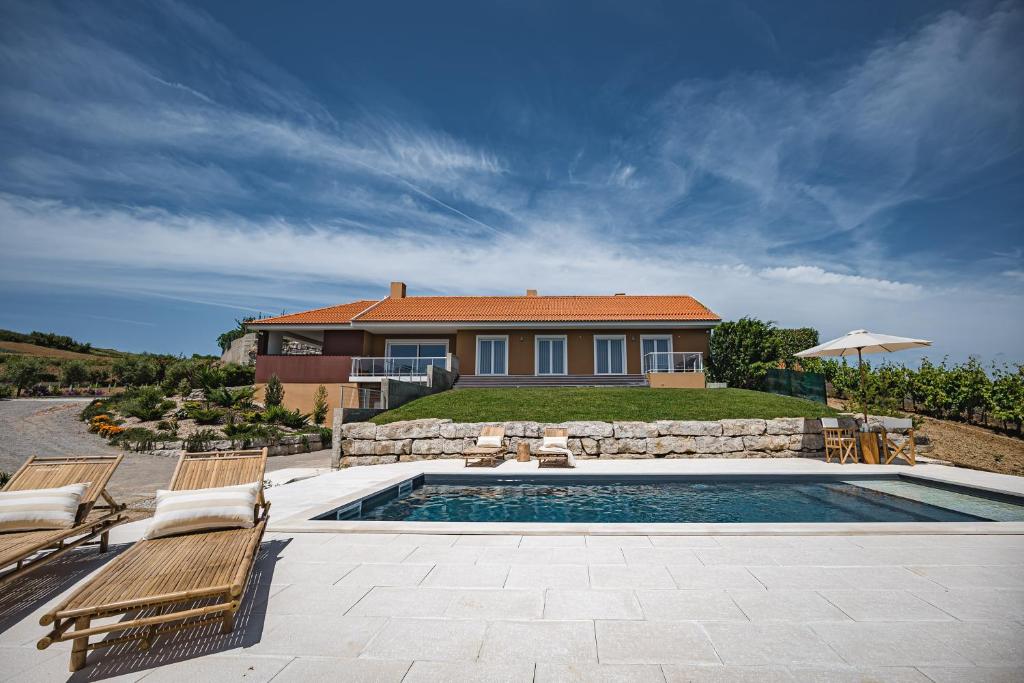 a house with a swimming pool and some chairs and a house at Advania Country House in Lourinhã