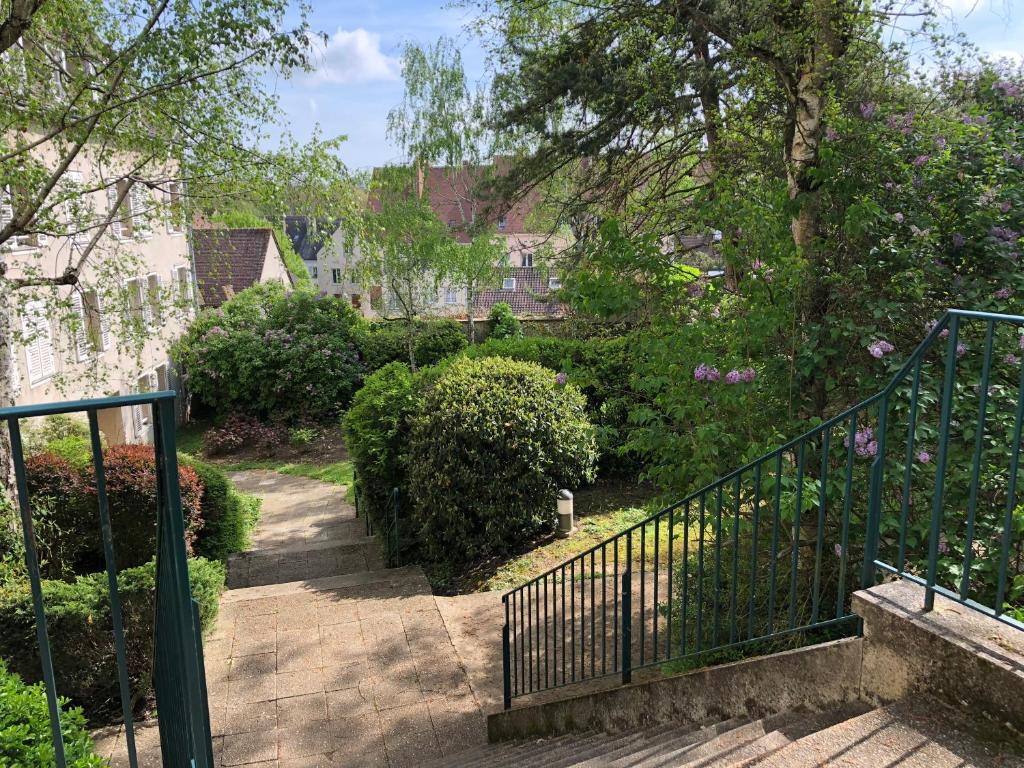 Un escalier mène à un jardin avec des buissons et des arbres. dans l'établissement LE SEUIL, à Chartres