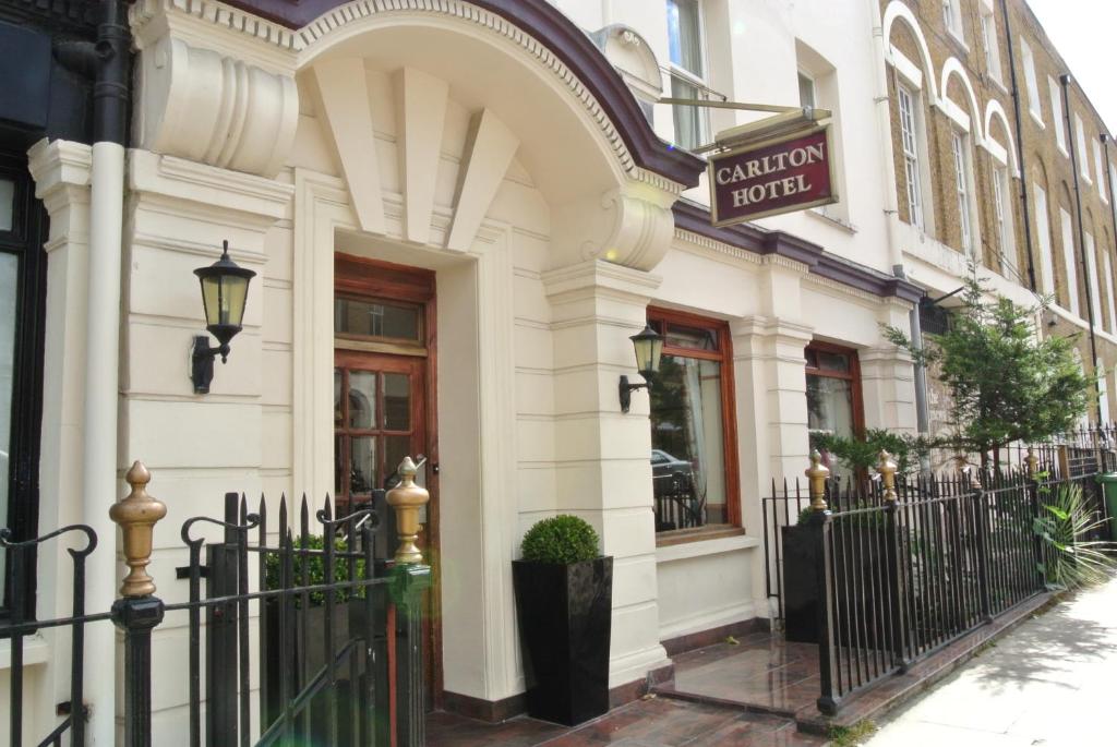 un bâtiment blanc avec une clôture noire devant lui dans l'établissement Carlton Hotel, à Londres