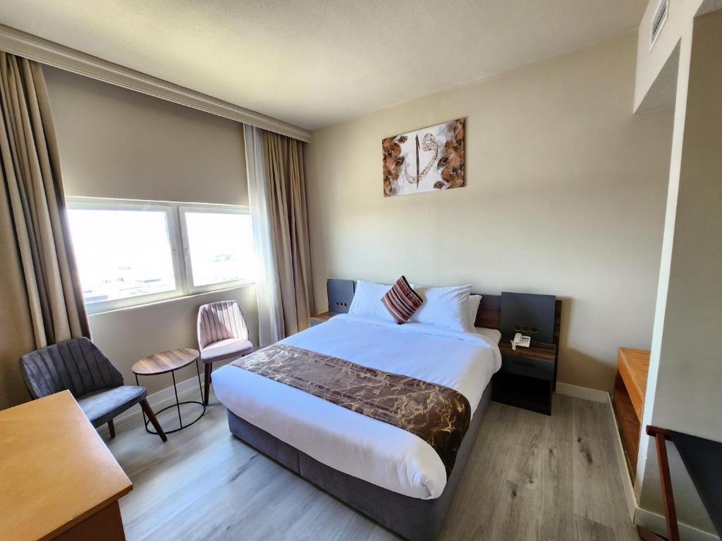 The Saj Hotel في عجمان: غرفة فندقية بسرير وطاولة وكراسي