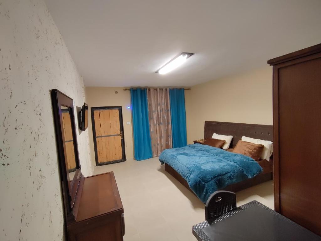 a bedroom with a bed with a blue comforter at Sail Alhasa Tourist Resort-Tafila in At-Tafilah