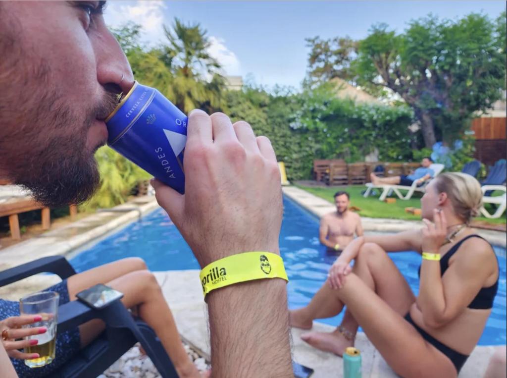 un hombre bebiendo de una botella de agua azul en Gorilla Hostel en Mendoza