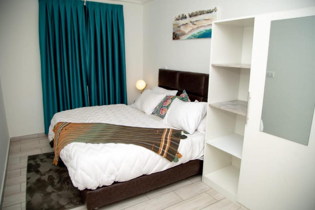ein Schlafzimmer mit einem Bett mit einem blauen Vorhang in der Unterkunft 1995 Apartment in Accra