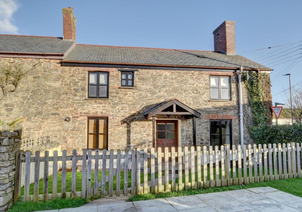 an old brick house with a white picket fence at Cross Farm Cottage in Braunton