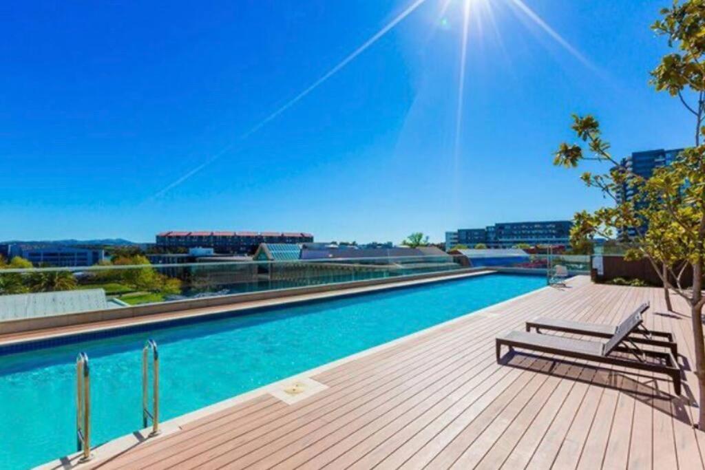 a swimming pool with a bench on a wooden deck at Plush @ Benjamin way Belconnen in Belconnen
