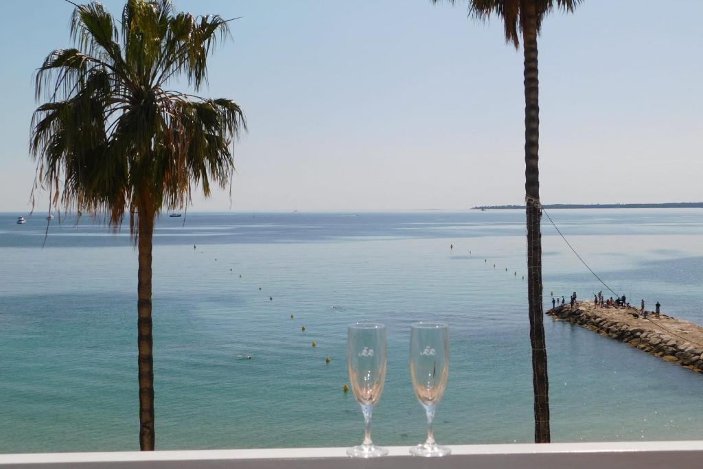 two wine glasses sitting on a table next to the ocean at Splendid T2 "San Remo" waterfront air-conditioned and with parking in Juan-les-Pins