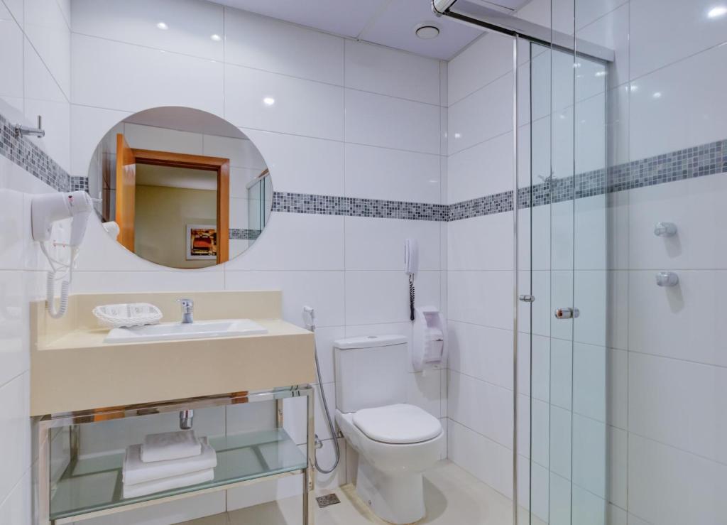 a bathroom with a toilet and a sink and a mirror at Rio Aeroporto Hotel Galeão in Rio de Janeiro