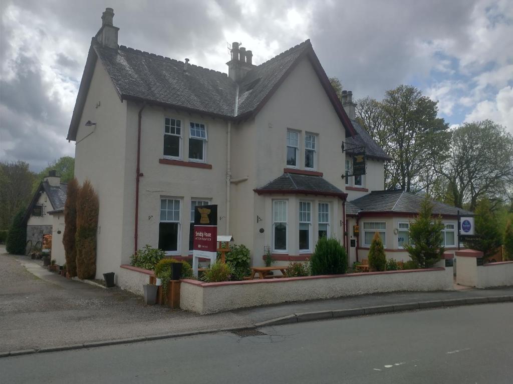 a white house sitting on the side of a street at Smiddy House in Spean Bridge