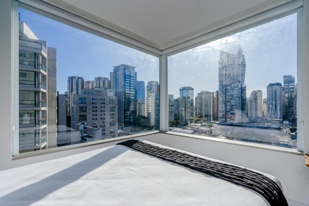 a bedroom with a large window with a view of the city at Tabas - VN Ferreira Lobo in São Paulo