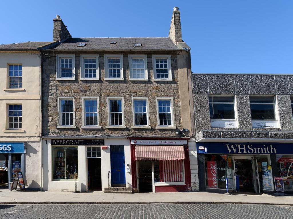 an old brick building on a street with shops at Horsemarket Apartment in Kelso