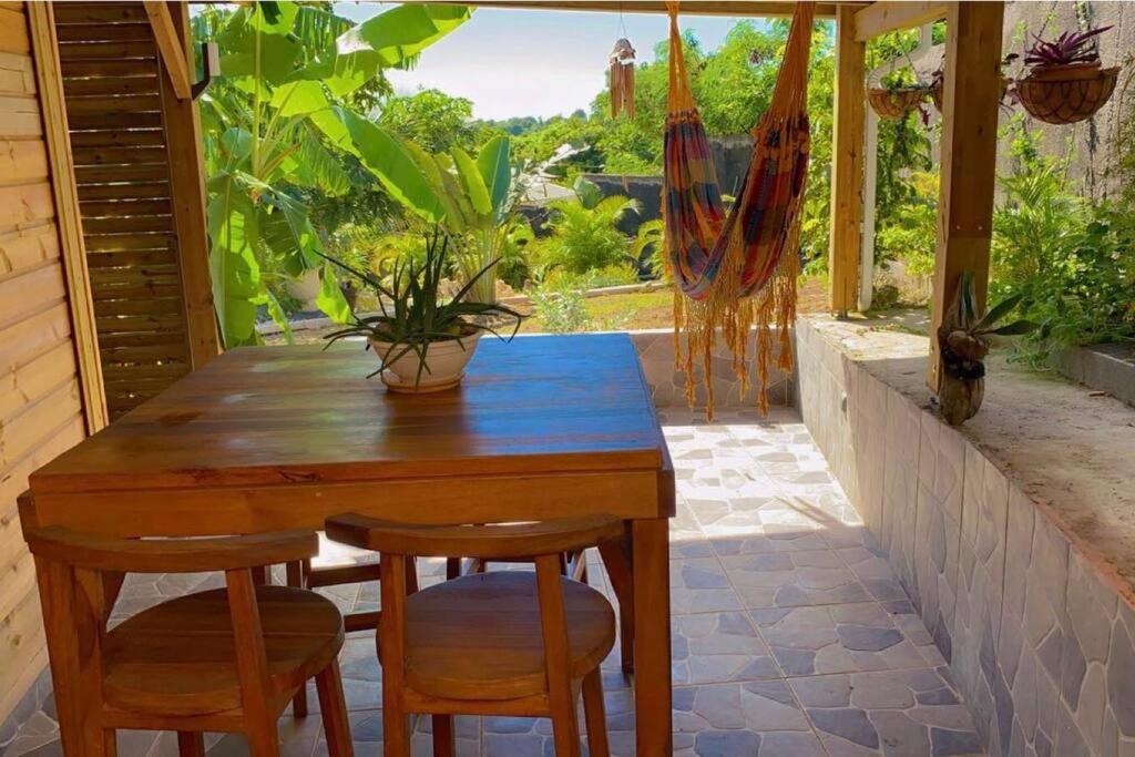 una mesa de madera y sillas en un patio con ventana en Banana EcoLodge, en Saint-François