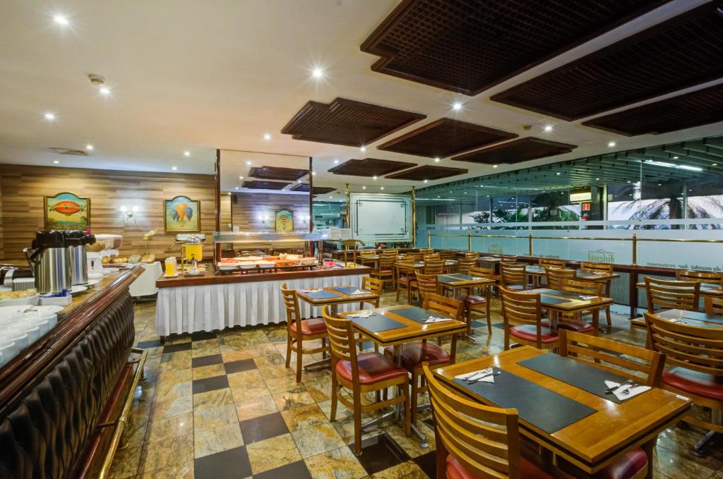 a restaurant with tables and chairs and a kitchen at Rio Aeroporto Hotel Galeão in Rio de Janeiro