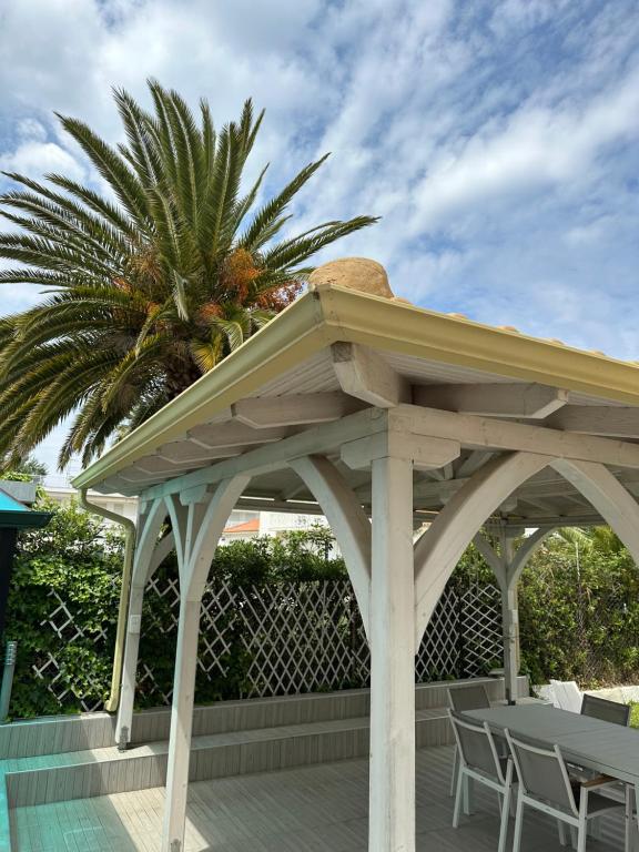 a wooden gazebo on a patio with a palm tree at Sea Wave House in Hanioti