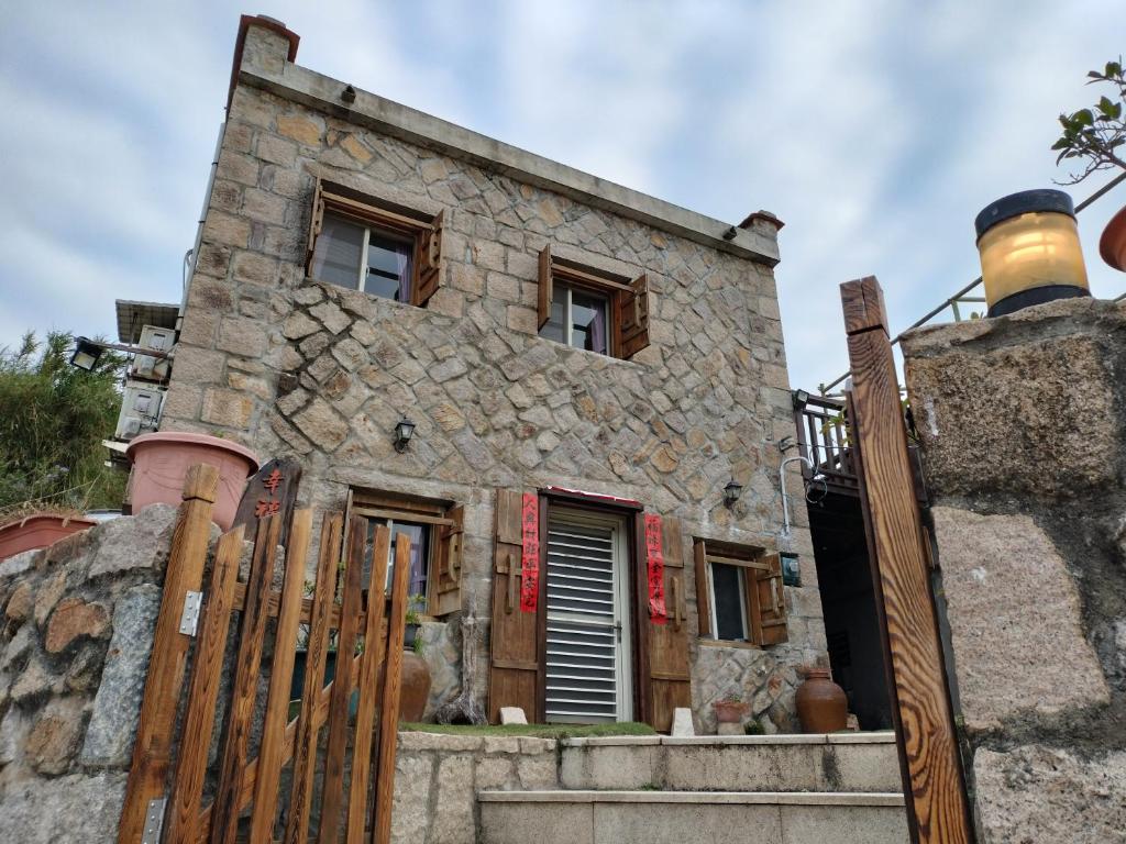 una vieja casa de piedra detrás de una valla de madera en Happy Inn, en Juguang