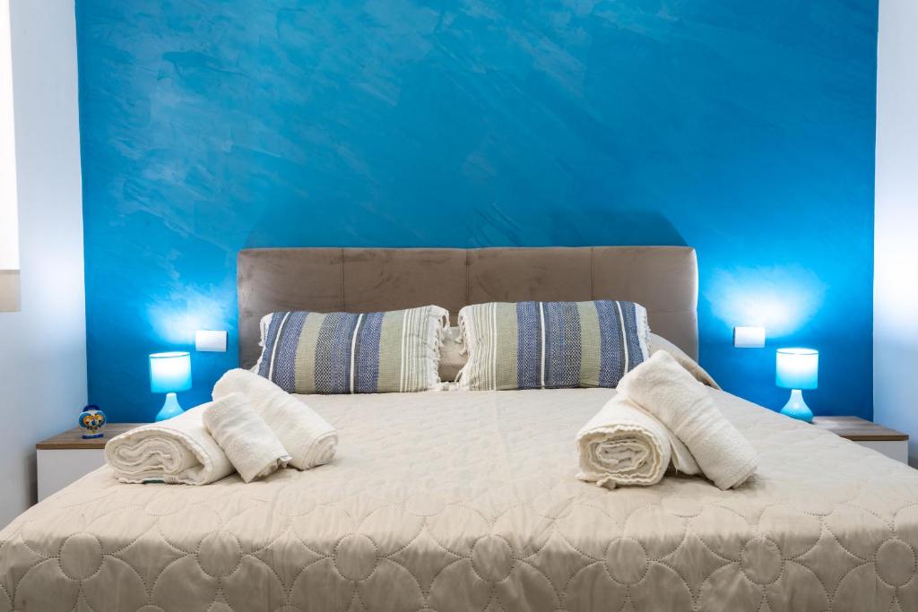 1 dormitorio azul con 1 cama grande con almohadas blancas en Napul'è B&B, en Boscotrecase