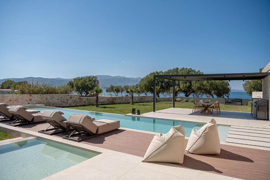 a swimming pool with chaise lounge chairs next to a swimming pool at Pnoe Villas - Seafront Experience in Tavronitis