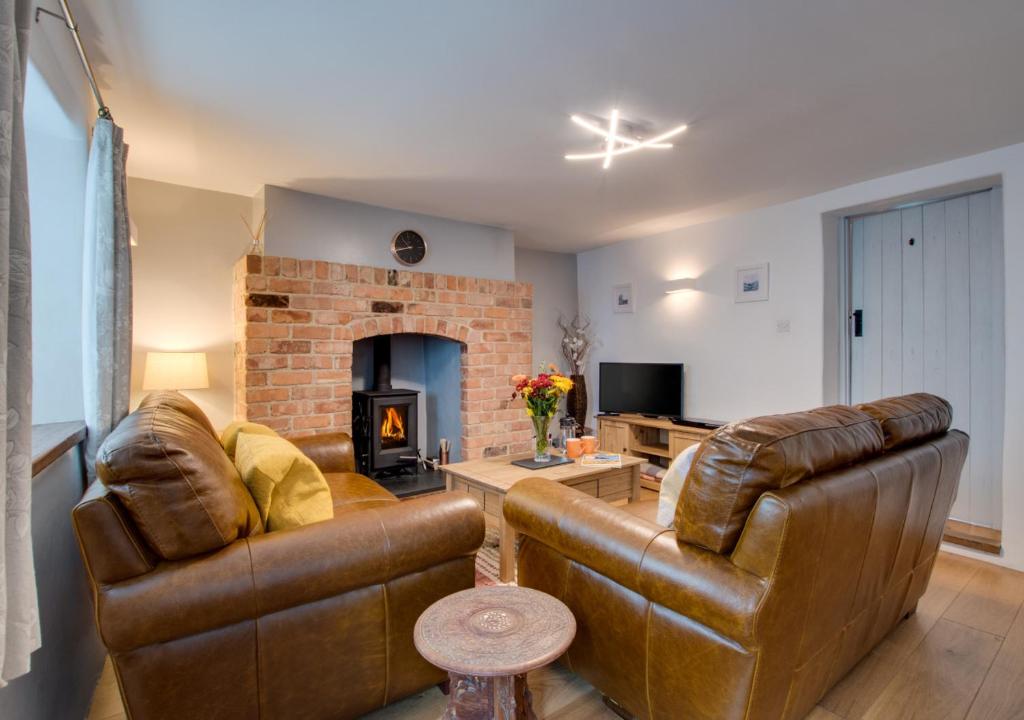 a living room with two leather couches and a fireplace at Dolphin Cottage in Braunton