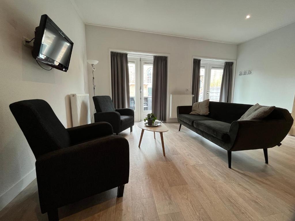 a living room with a couch and chairs and a tv at Appartementen het Centrum in Domburg