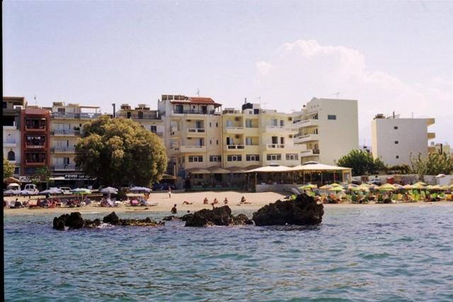 a group of people on a beach with buildings at Nea Elena Apartments in Chania