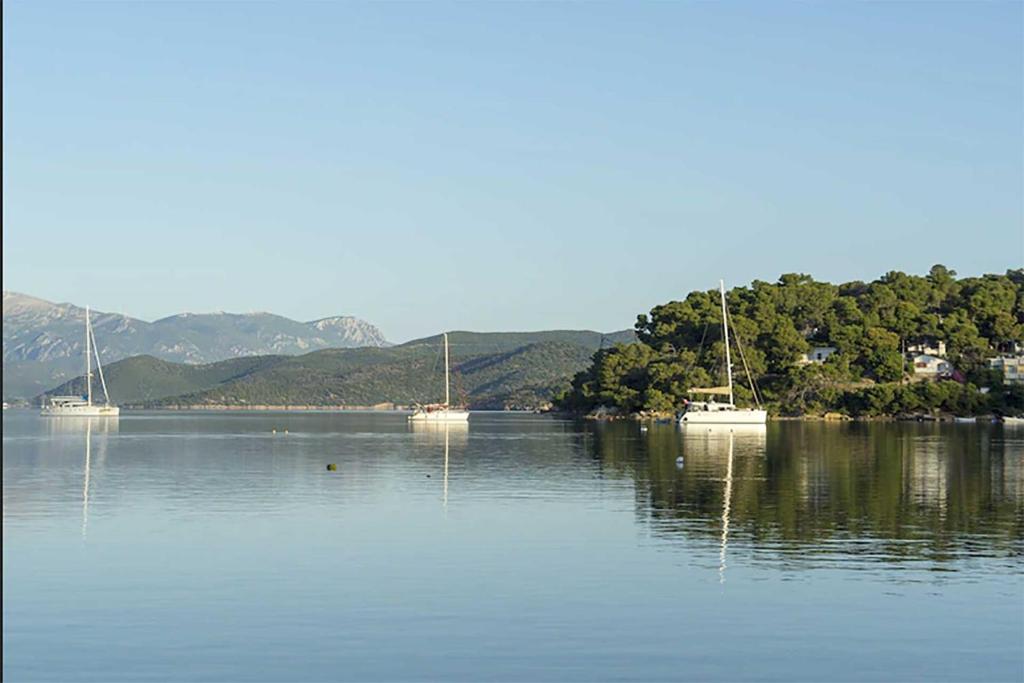 Tre barche sono sedute su un grande corpo d'acqua di Ancora Hotel a Poros