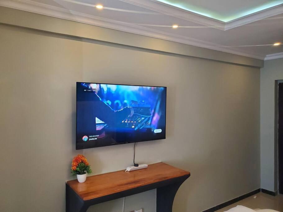 a flat screen tv hanging on a wall at Cozy Studio Stay Kilimani Valley Acarde Area in Nairobi