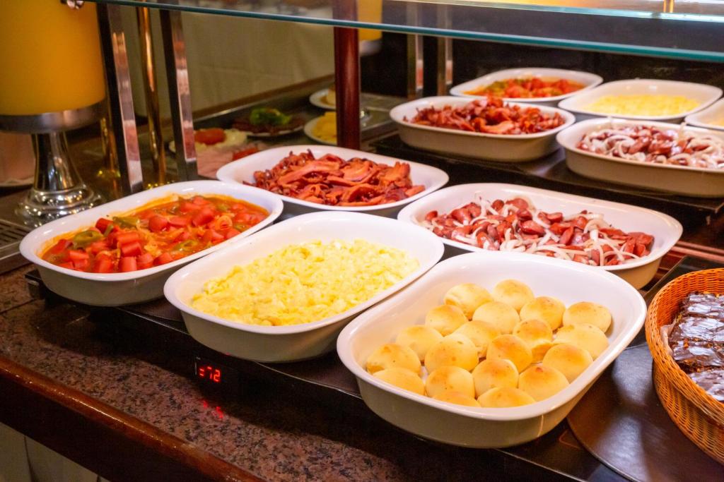 a buffet filled with bowls of different types of food at Rio Aeroporto Hotel Galeão in Rio de Janeiro