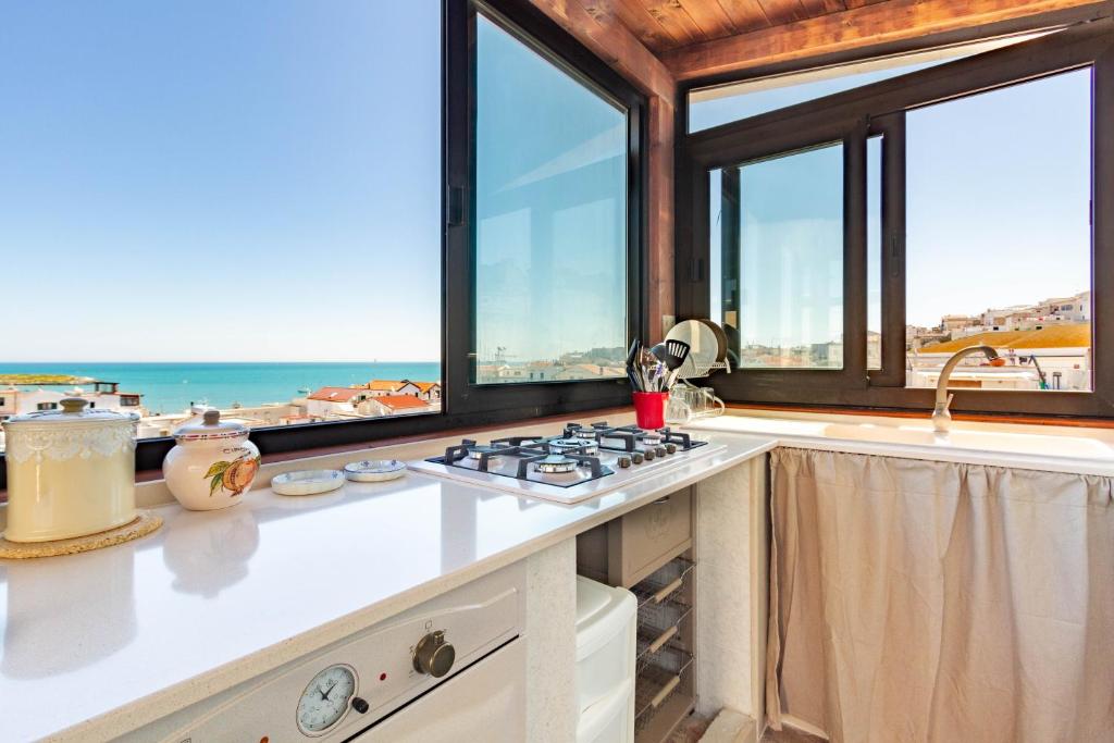 cocina con ventanas y vistas al océano en Appartamento Il Belvedere - MyHo Casa, en Vieste