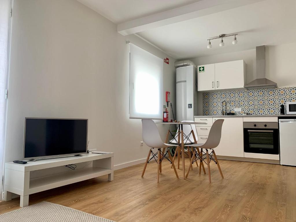 uma cozinha com uma televisão e uma mesa e cadeiras em Apartamento Sta Maria - Sta Catarina Place em Ponta Delgada