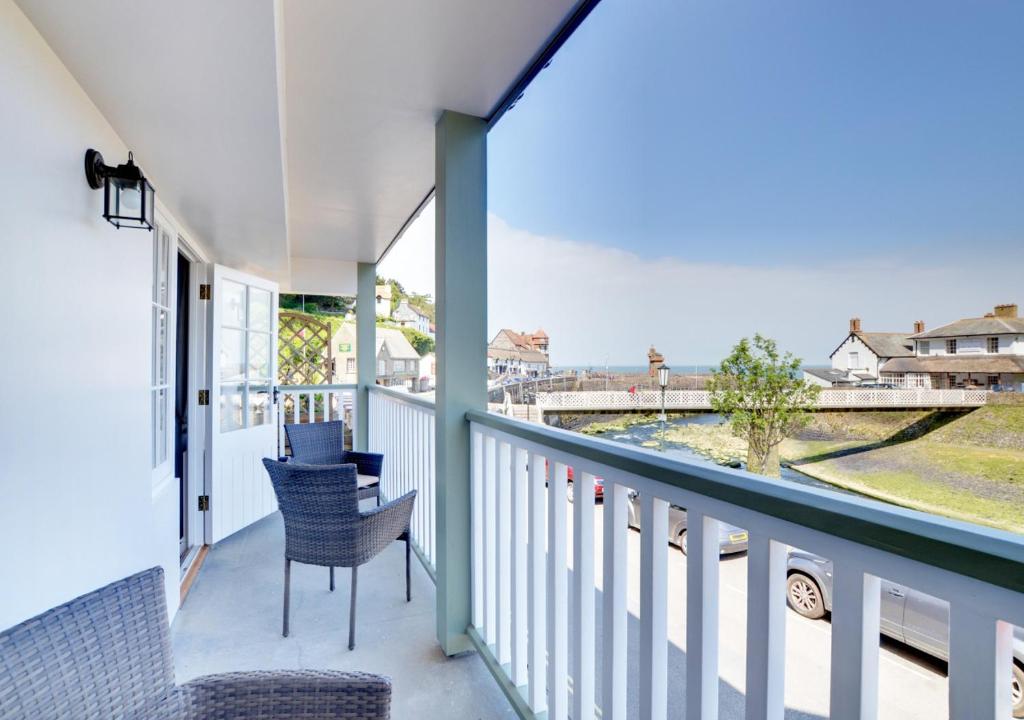 a balcony with chairs and a view of the water at Harbour View Lynmouth in Lynmouth