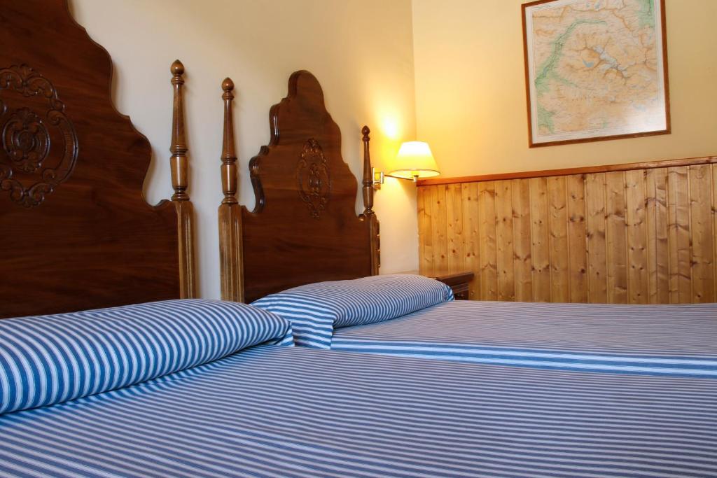 a bedroom with two beds with blue and white stripes at Hotel Delavall in Vielha