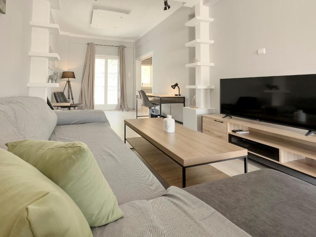 ein Wohnzimmer mit einem Sofa, einem TV und einem Tisch in der Unterkunft Iakovaton Modern 62sqm in Athens in Athen