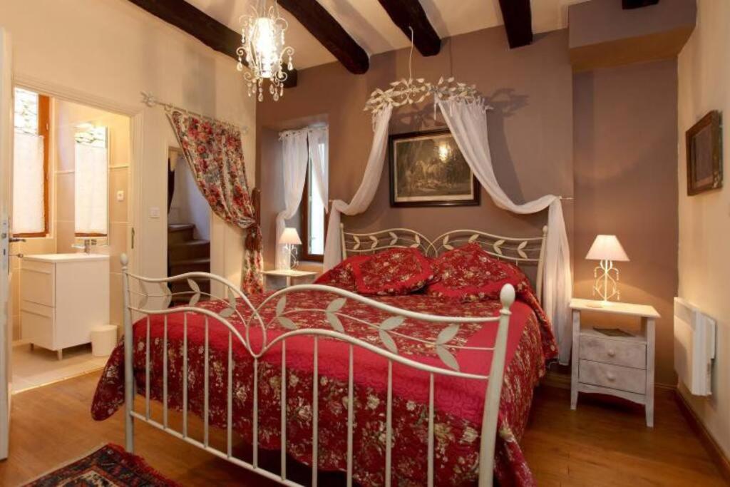 um quarto com uma cama vermelha e um lustre em Sarlat Town House, gîte de charme em Sarlat-la-Canéda