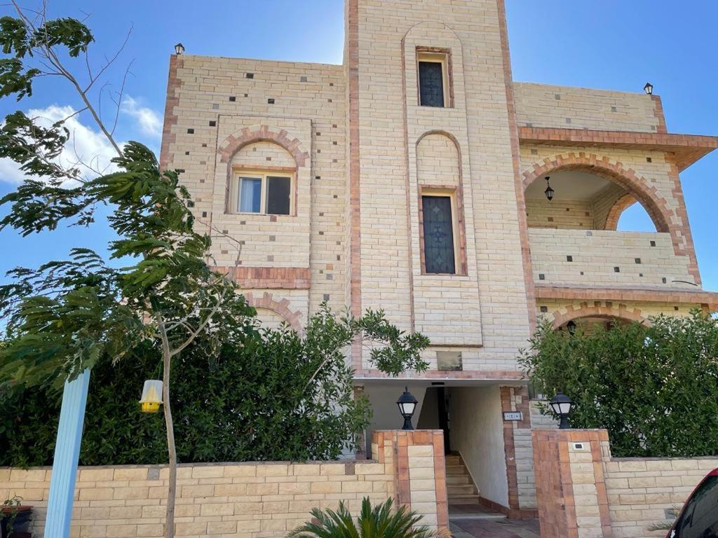 a large brick building with a tree in front of it at Seaview luxury Villa in Ras El Hekhma - North Coast in Ras Elhekma