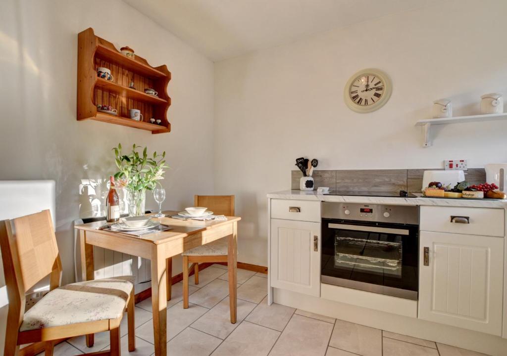 cocina con mesa, fogones y comedor en Kingfisher Cottage, en East Down