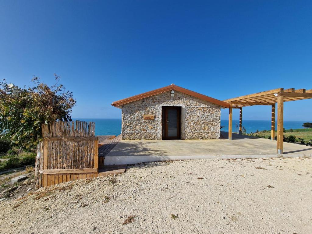 un piccolo edificio su una spiaggia con l'oceano sullo sfondo di Tendu' Punta Bianca Glamping Camp a Palma di Montechiaro
