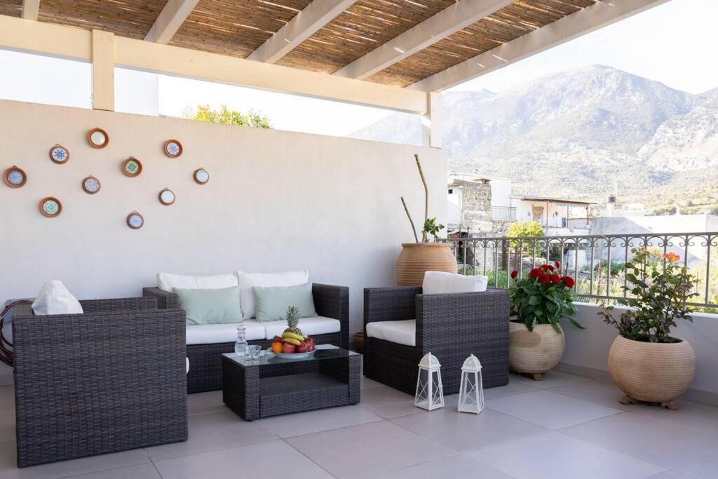 a patio with a couch and chairs and a table at Merastri Villa in Zaros