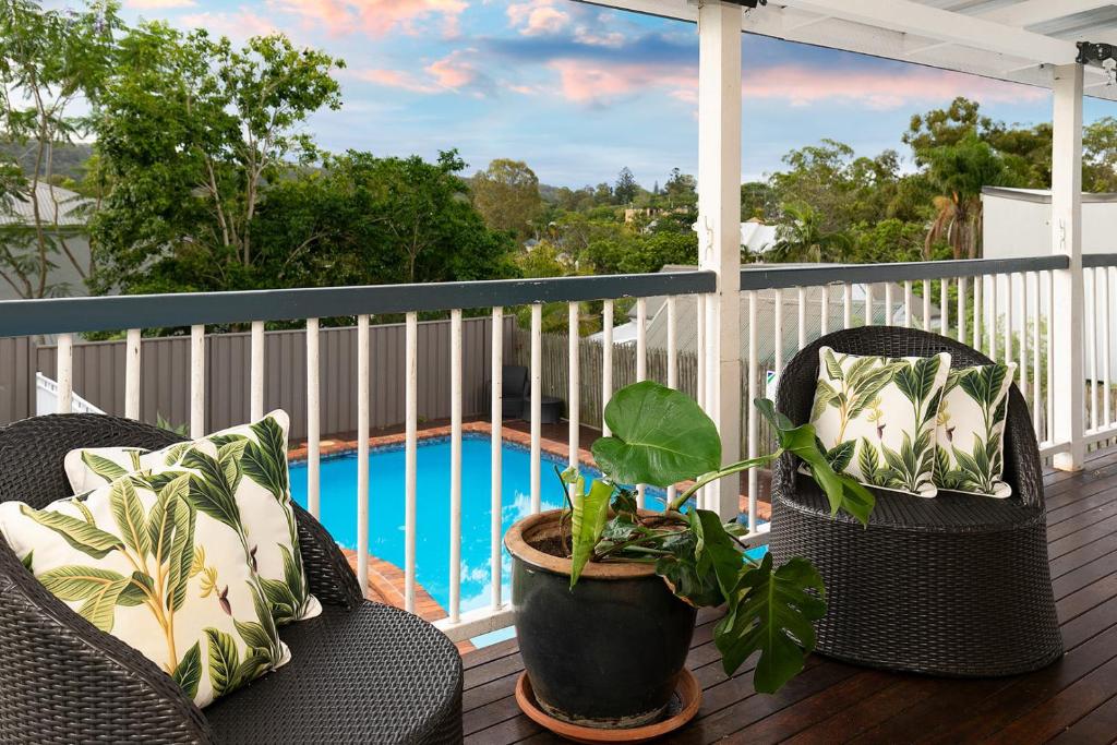 布里斯本的住宿－The Indooroopilly Queenslander - 4 Bedroom Family Home - Private Pool - Wifi - Netflix，一个带两把椅子的阳台和一个游泳池