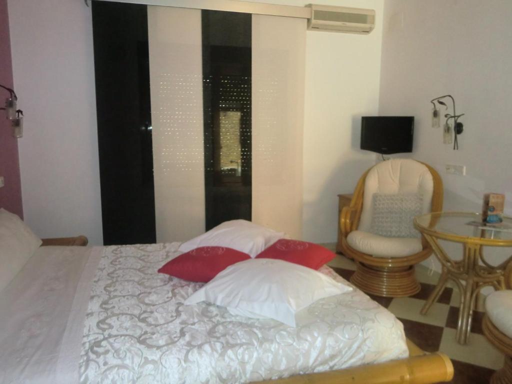 a bedroom with a bed with red pillows and a chair at Hotel Gasaqui in Ayelo de Malferit