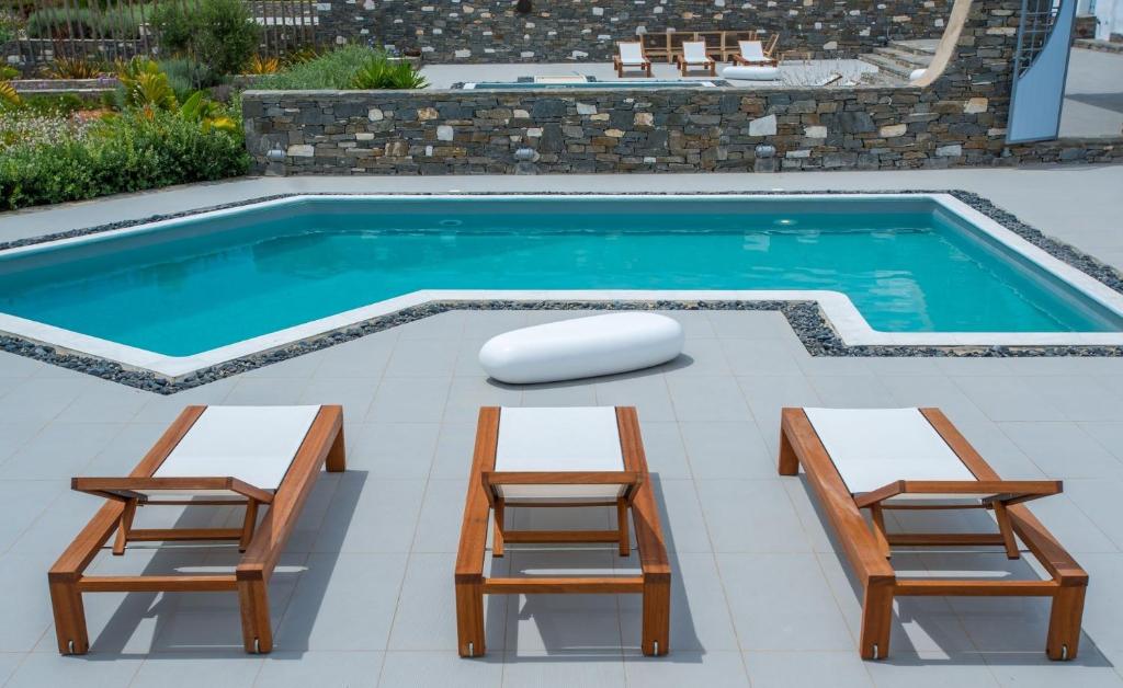a swimming pool with two chairs and a table and a bench at Deluxe Paros Villa Grand Villa Sea View Private Pool 4 BDR Tserdakia in Kampos Paros