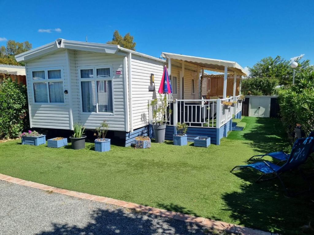 une petite maison blanche avec des plantes dans une cour dans l'établissement L'Exellence, à Fréjus