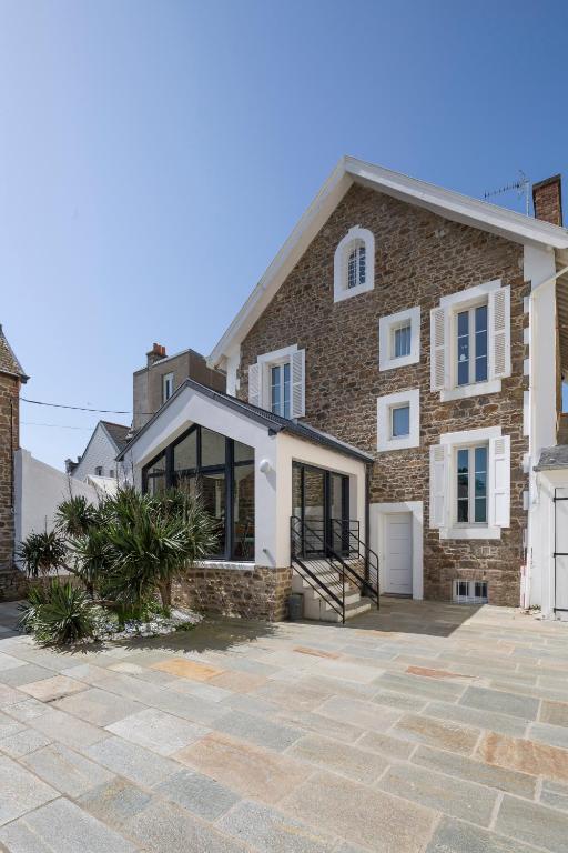 une grande maison en pierre avec une allée en pierre dans l'établissement Villa Sainte Geneviève, à Saint-Malo