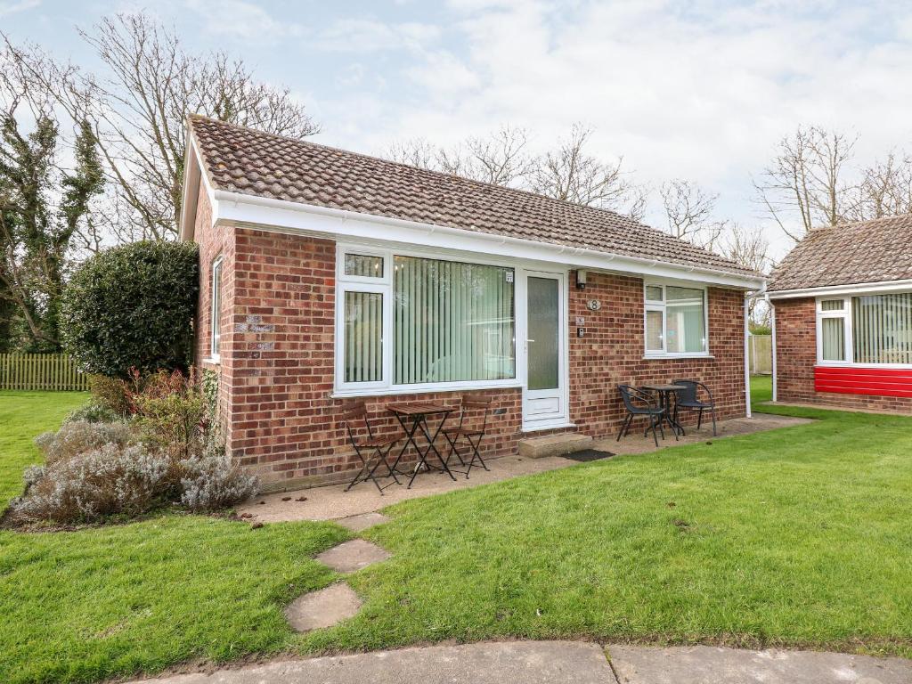 a brick house with a table and chairs in a yard at 8 Royal Chalet Park in Norwich