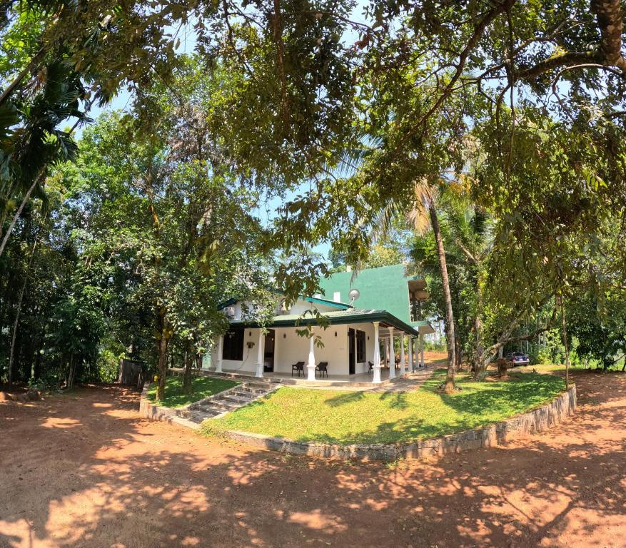 una pequeña casa blanca con techo verde en Leon Hilltop Resort, en Kitulgala