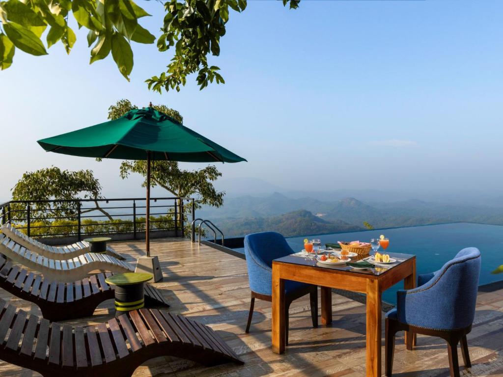 a deck with chairs and a table and an umbrella at GreenAcres Leisure Resort in Kandy