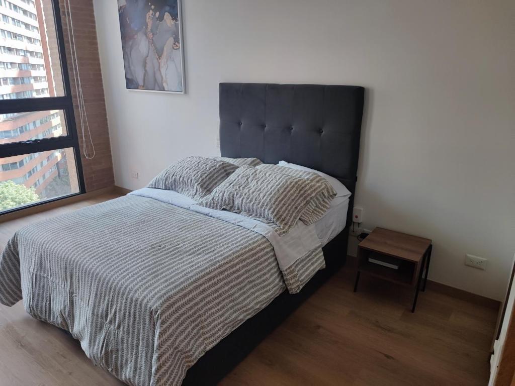 um quarto com uma cama com uma cabeceira preta em Aparta Suite - Centro Internacional - Mitika em Bogotá