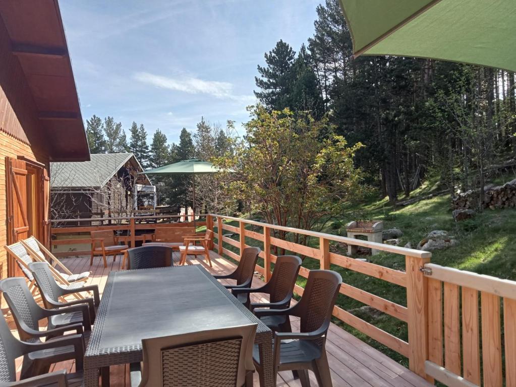 drewniany taras ze stołem i krzesłami w obiekcie Chalet de montagne w mieście Formiguères