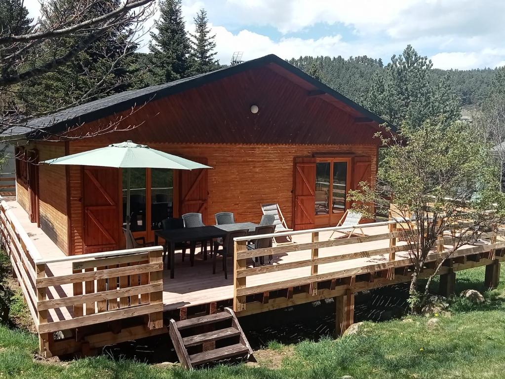 une cabine en bois avec une terrasse et un parasol dans l'établissement Chalet de montagne, à Formiguères