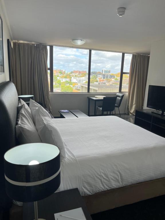 a hotel room with a bed and a large window at Prestige Hyde Park Studio Apartment in Sydney