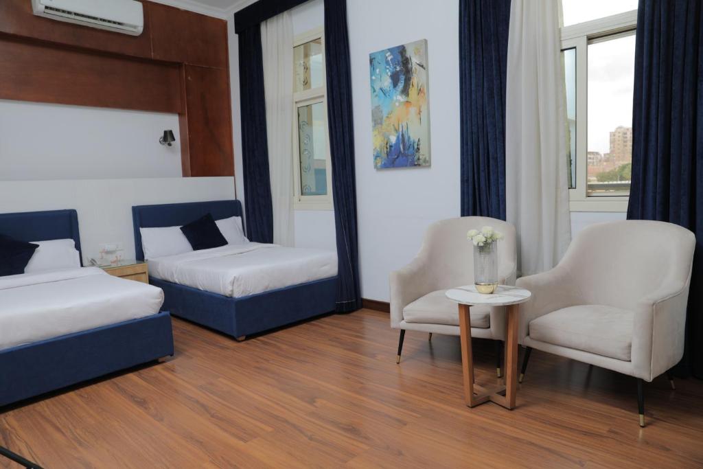 a bedroom with two beds and a table and chairs at Loaloat Nile Corniche El maadi in Cairo