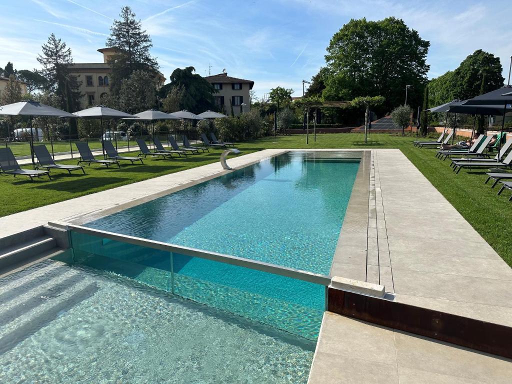 a large swimming pool with chairs and umbrellas at Hotel Palazzo San Lorenzo & Spa in Colle Val D'Elsa